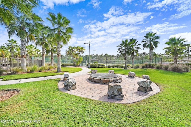 view of property's community featuring a lawn, a patio area, and a fire pit