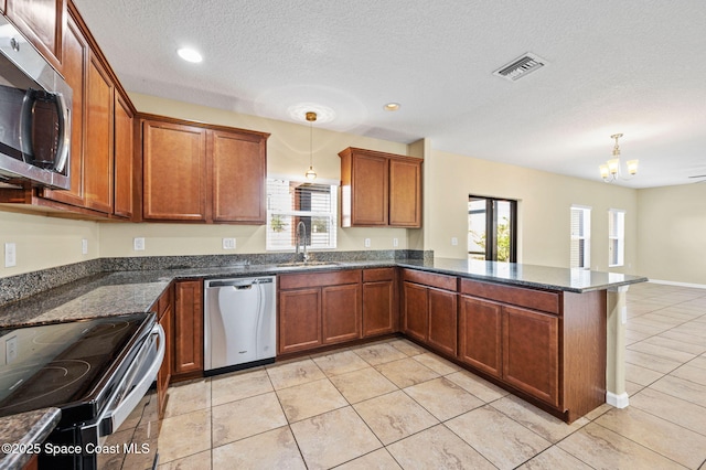 kitchen featuring hanging light fixtures, sink, kitchen peninsula, and appliances with stainless steel finishes