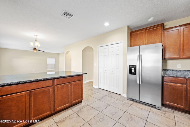 kitchen with stainless steel fridge, ceiling fan, dark stone countertops, a textured ceiling, and light tile patterned flooring