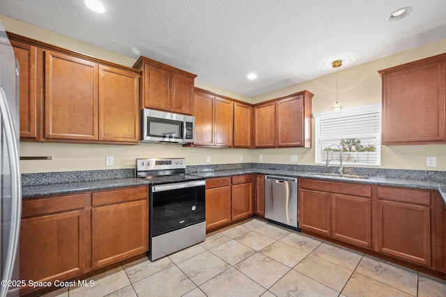 kitchen with stainless steel appliances, light tile patterned flooring, sink, and a textured ceiling