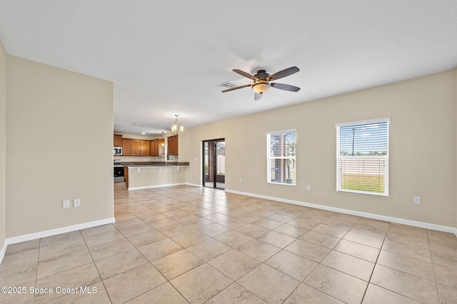 unfurnished living room with ceiling fan with notable chandelier and light tile patterned flooring