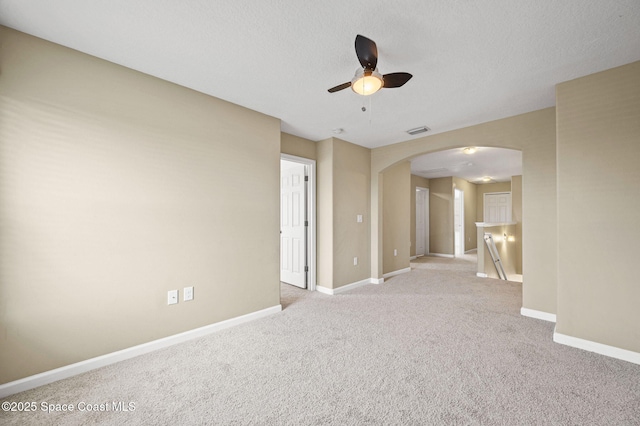 empty room featuring ceiling fan, light colored carpet, and a textured ceiling