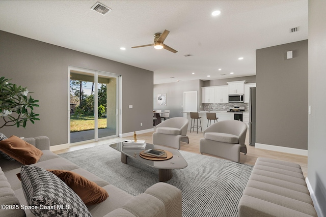 living room featuring light hardwood / wood-style flooring and ceiling fan