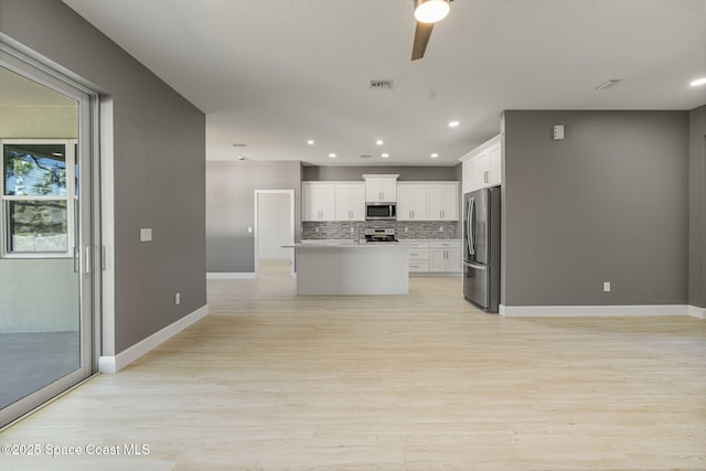 kitchen featuring a kitchen island, appliances with stainless steel finishes, white cabinetry, decorative backsplash, and ceiling fan