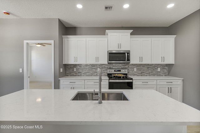 kitchen with light stone counters, stainless steel appliances, sink, and white cabinets