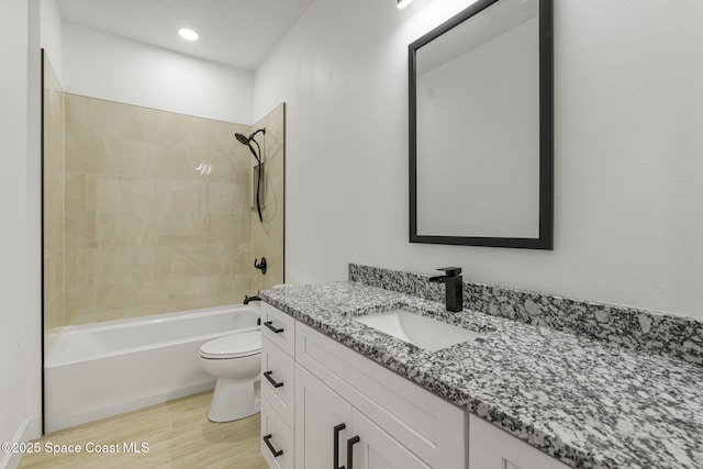 full bathroom featuring tiled shower / bath, wood-type flooring, toilet, and vanity