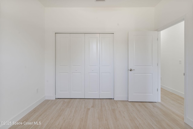 unfurnished bedroom featuring a closet and light wood-type flooring