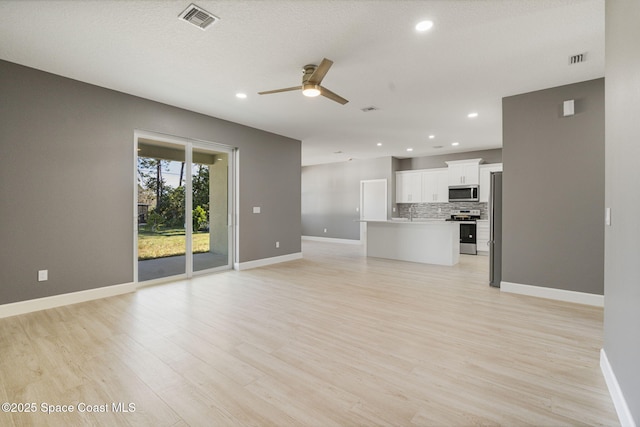 unfurnished living room with ceiling fan and light hardwood / wood-style floors