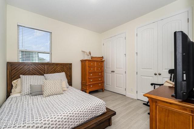 bedroom with multiple closets and light wood-type flooring