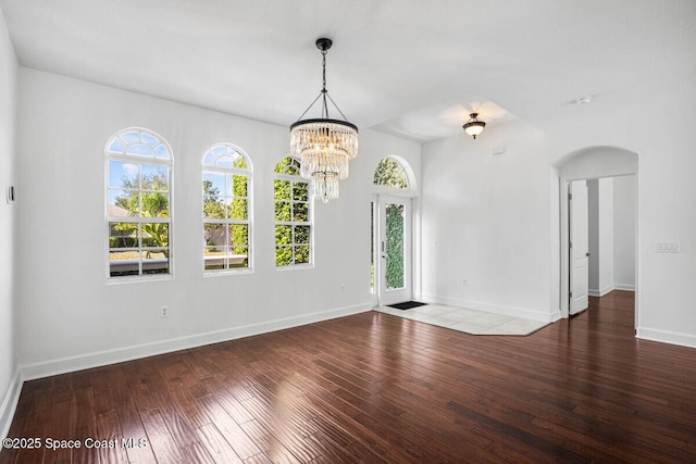 spare room featuring an inviting chandelier and hardwood / wood-style floors