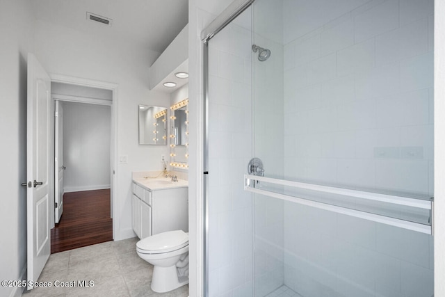 bathroom featuring walk in shower, vanity, toilet, and tile patterned flooring