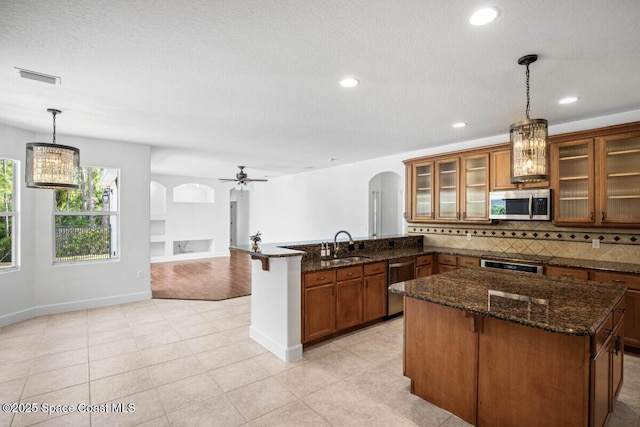 kitchen featuring a breakfast bar, tasteful backsplash, kitchen peninsula, pendant lighting, and stainless steel appliances