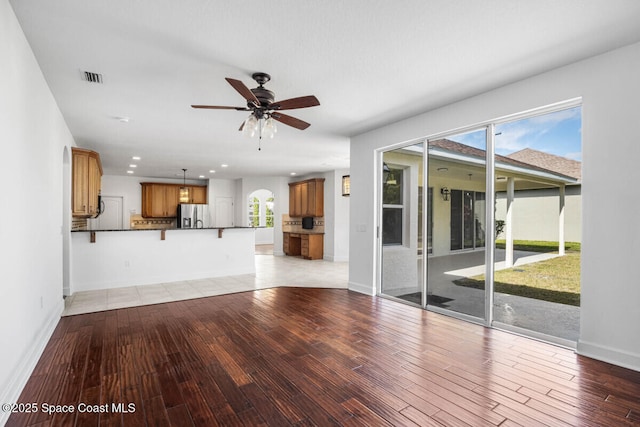 unfurnished living room featuring ceiling fan and light wood-type flooring