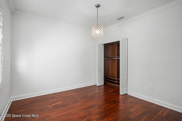 empty room with ornamental molding, dark hardwood / wood-style floors, and an inviting chandelier