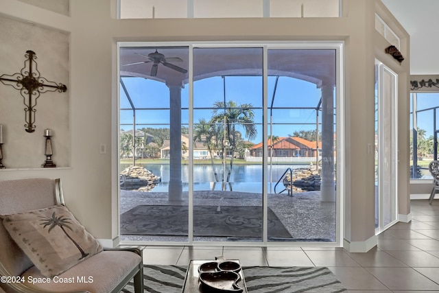 doorway to outside featuring a water view, ceiling fan, and tile patterned flooring