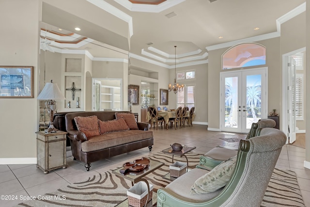 tiled living room with crown molding, a towering ceiling, a chandelier, and french doors