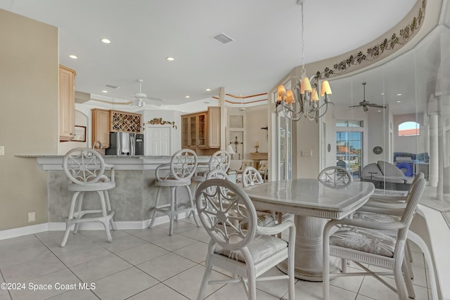 tiled dining space featuring ceiling fan with notable chandelier