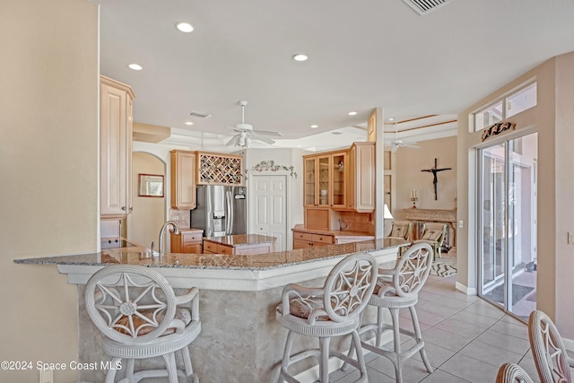 kitchen with a kitchen bar, kitchen peninsula, ceiling fan, and stainless steel refrigerator with ice dispenser