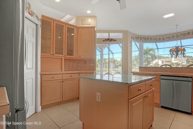 kitchen featuring light stone counters, a kitchen island, stainless steel appliances, ceiling fan with notable chandelier, and backsplash