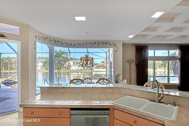 kitchen featuring a wealth of natural light, a water view, sink, and tile counters