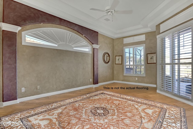 unfurnished room featuring ceiling fan and a raised ceiling