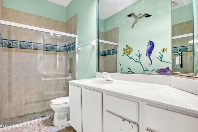 bathroom with tile patterned flooring, vanity, a shower with door, and toilet