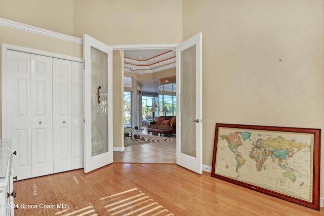 interior space with hardwood / wood-style floors, crown molding, french doors, and a high ceiling