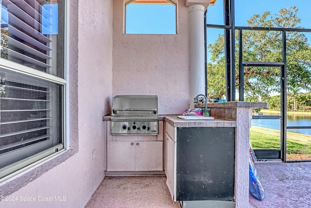 view of patio / terrace featuring a water view, grilling area, a bar, and area for grilling