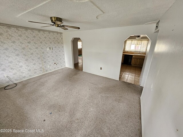 unfurnished room featuring ceiling fan, carpet floors, sink, and a textured ceiling