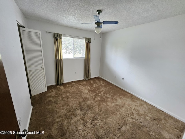 unfurnished bedroom with ceiling fan, dark carpet, and a textured ceiling