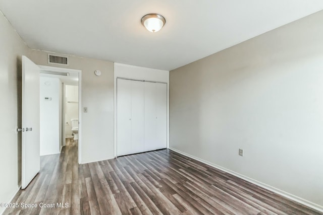 unfurnished bedroom featuring dark wood-type flooring and a closet