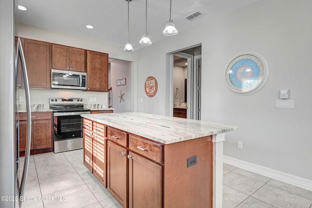 kitchen with a center island, hanging light fixtures, light tile patterned floors, appliances with stainless steel finishes, and light stone countertops