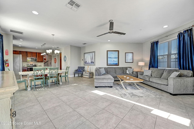 tiled living room with ceiling fan with notable chandelier