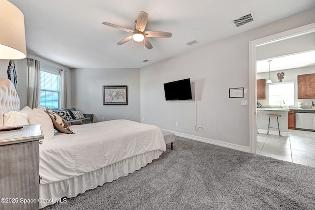 bedroom featuring light carpet, sink, ensuite bath, and ceiling fan