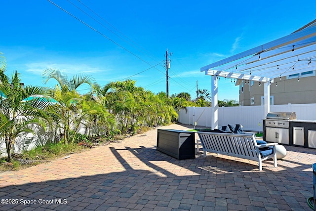 view of patio with area for grilling, a grill, and a pergola