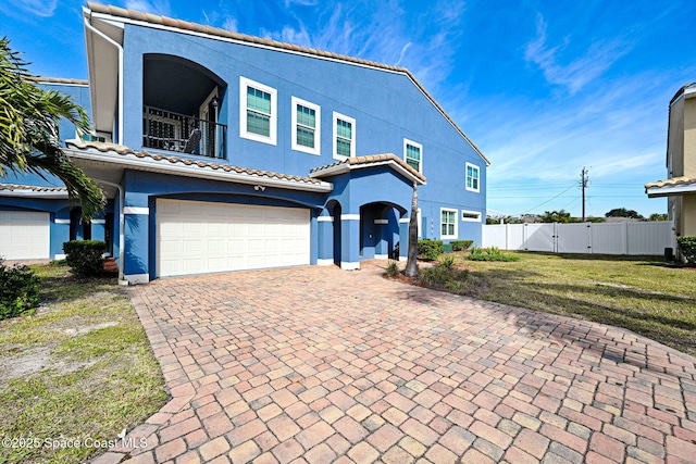 view of front of home with a balcony, a garage, and a front lawn