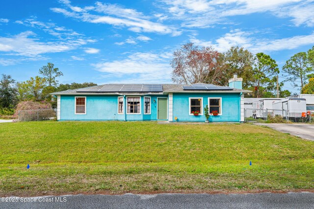 ranch-style home featuring solar panels and a front lawn