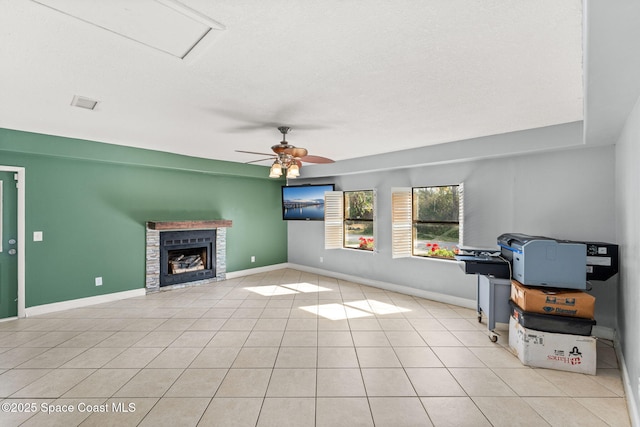 tiled living room with ceiling fan and a fireplace