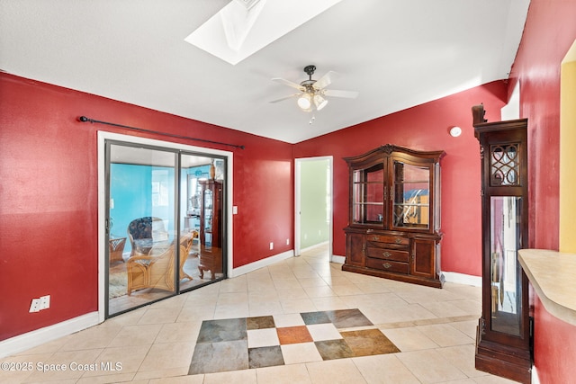 interior space featuring light tile patterned flooring, ceiling fan, and a skylight