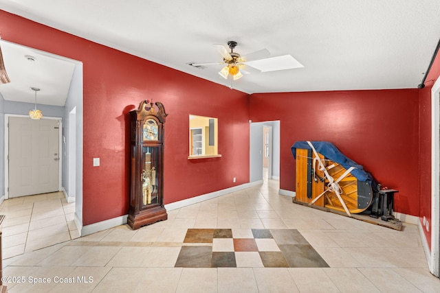 misc room featuring vaulted ceiling with skylight, ceiling fan, and light tile patterned floors