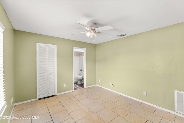 unfurnished bedroom featuring ensuite bath, light tile patterned floors, ceiling fan, and a closet