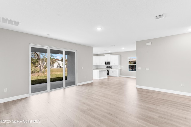 unfurnished living room featuring plenty of natural light and light hardwood / wood-style flooring