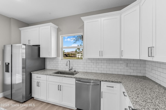 kitchen featuring light stone counters, sink, stainless steel appliances, and white cabinets