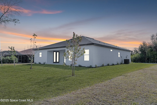 property exterior at dusk featuring a yard and central AC unit