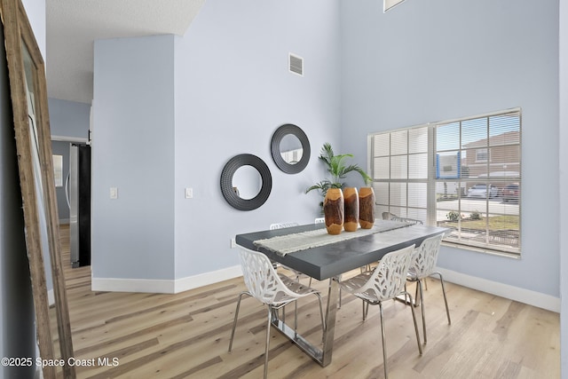 dining area with a towering ceiling and light wood-type flooring