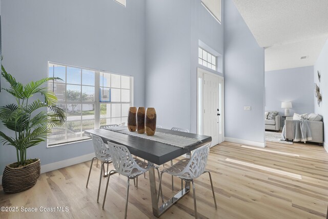 dining area featuring a towering ceiling and light hardwood / wood-style floors