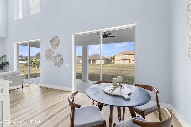 dining room featuring a high ceiling, ceiling fan, and light hardwood / wood-style floors