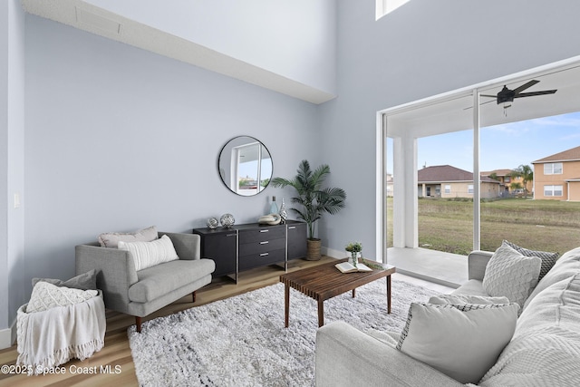 living room featuring wood-type flooring, a towering ceiling, and ceiling fan