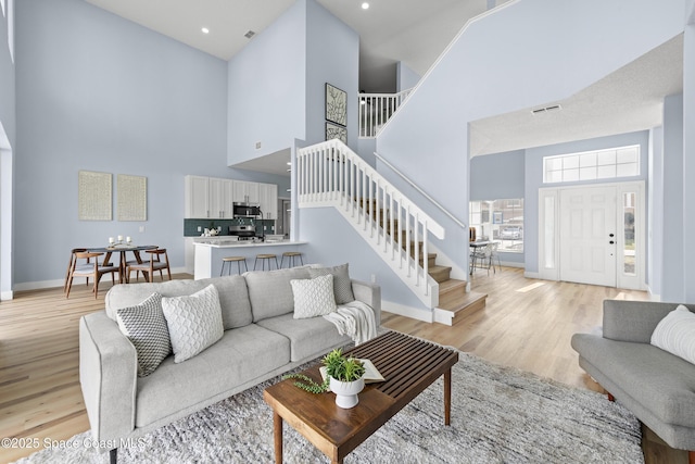 living room featuring a towering ceiling and light hardwood / wood-style flooring