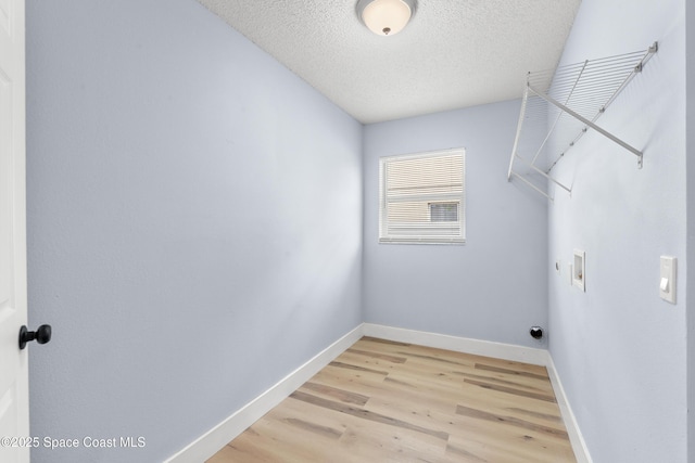 laundry area with light hardwood / wood-style floors, hookup for a washing machine, and a textured ceiling